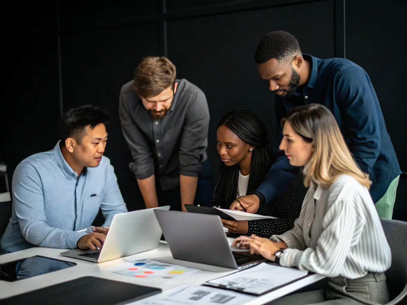 IT professionals working together in a collaborative workspace, with laptops and digital devices, used to represent Aventrix's Staff Augmentation Services.